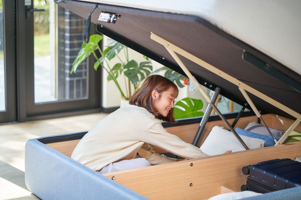 A person assembles IKEA furniture in a room with tools and parts spread out on a wooden floor.