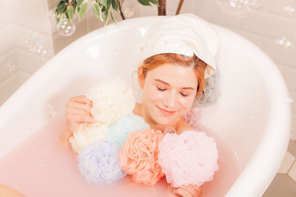 Cotton candy colored bath bombs dissolve in milky white bathwater creating a dreamy spa-like atmosphere.