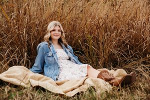 Maternity photo session in a golden field with tall grass and warm autumn lighting.