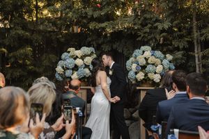 Bride and groom sharing their first kiss surrounded by family at a Pasadena wedding