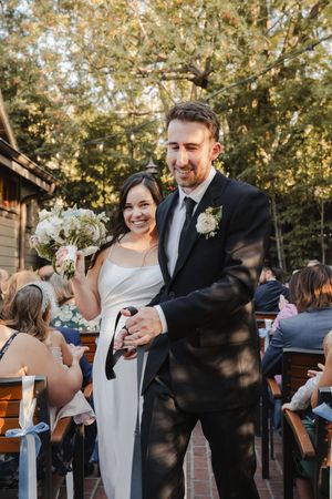Bride and groom leaving the ceremony surrounded by cheering family and friends
