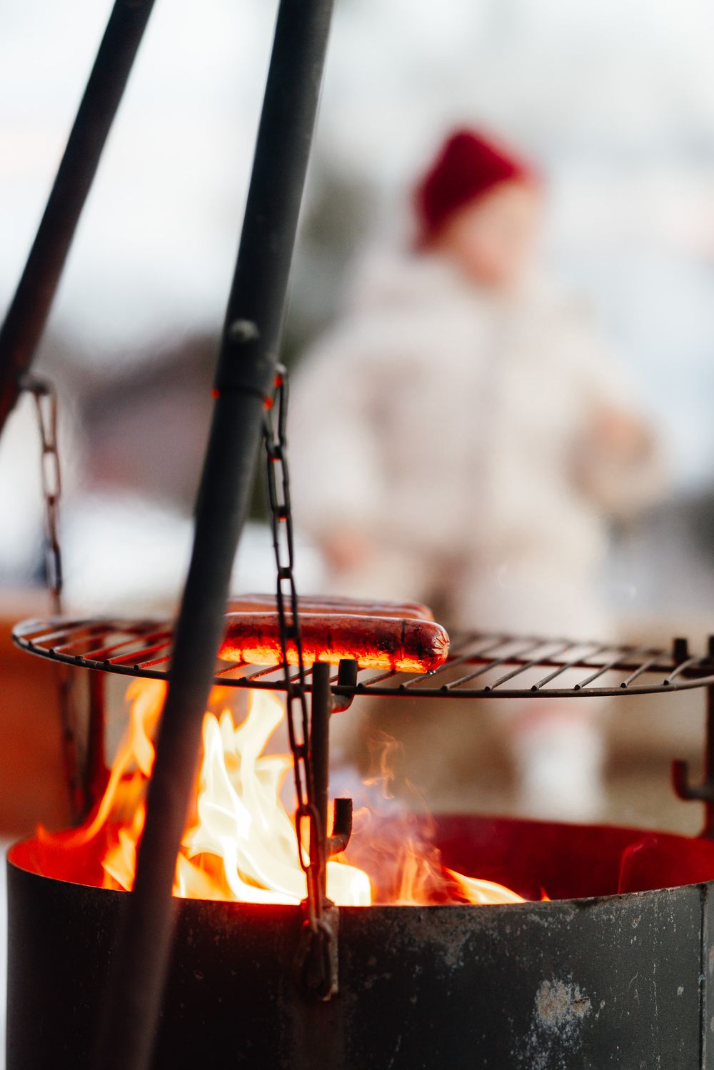Flames and smoke rise from a black grill grate during outdoor barbecue cooking.
