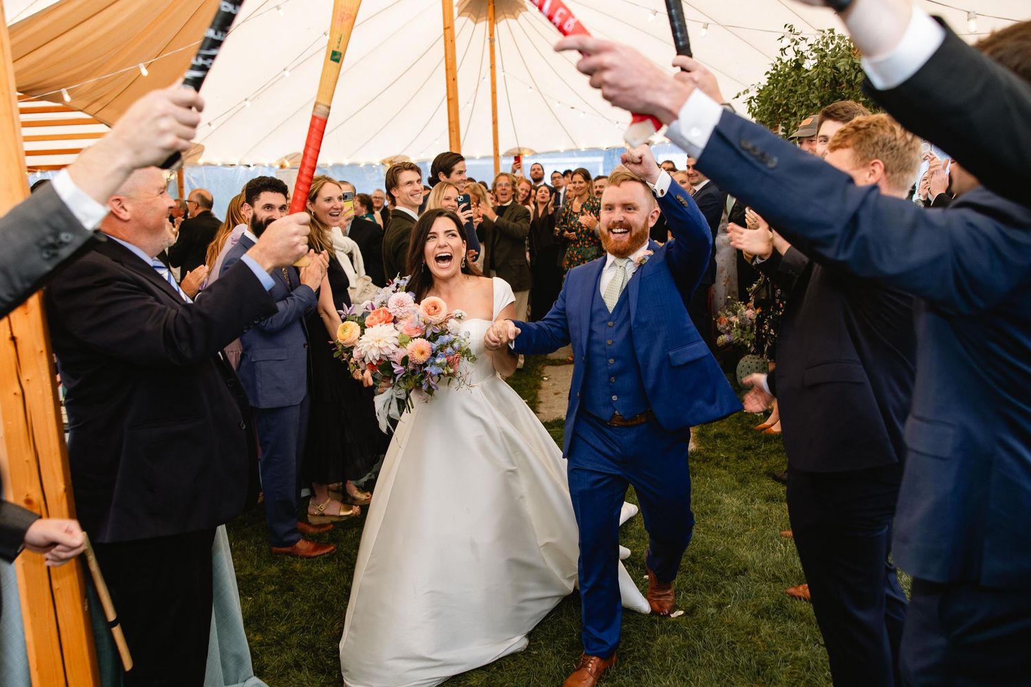 Wedding guests celebrate with sparklers during an outdoor evening reception under a tent.