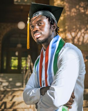 student who just graduated standing on the old main stairs.
