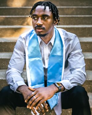 student who just graduated sitting on the old main stairs.