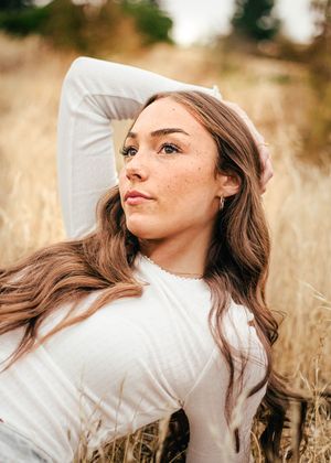 Girl lays casually in yellow grass.
