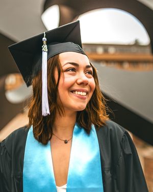 graduate posing in front of square statue
