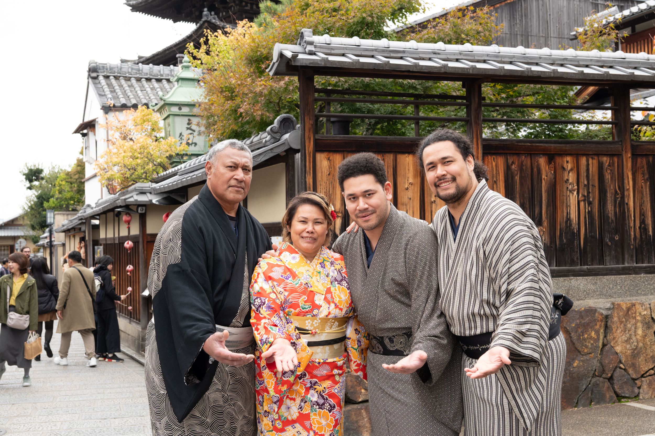 Family of four posing joyfully in traditional Japanese kimono on a historic street.