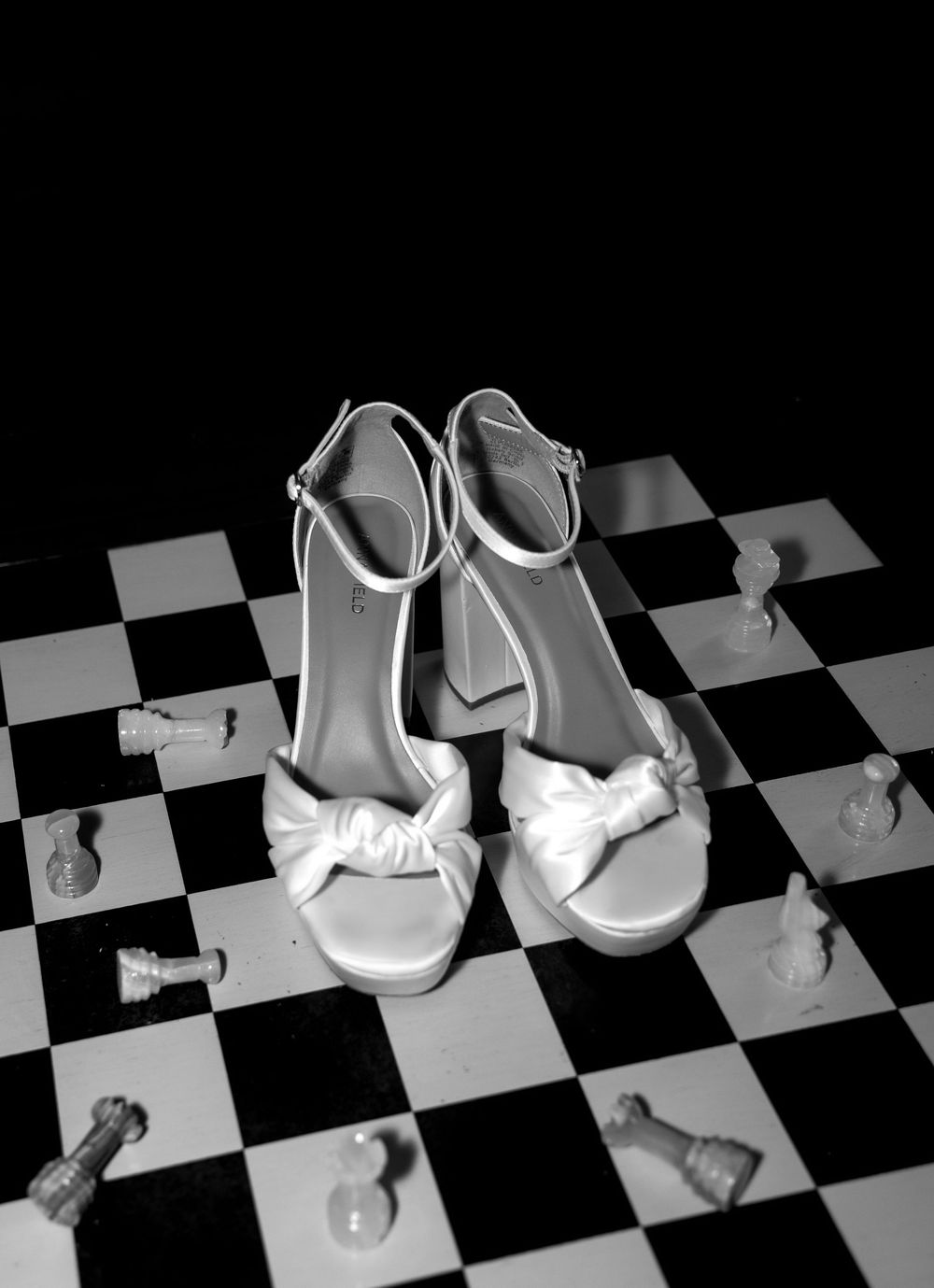 Wedding shoes arranged artistically on a black and white checkered floor.