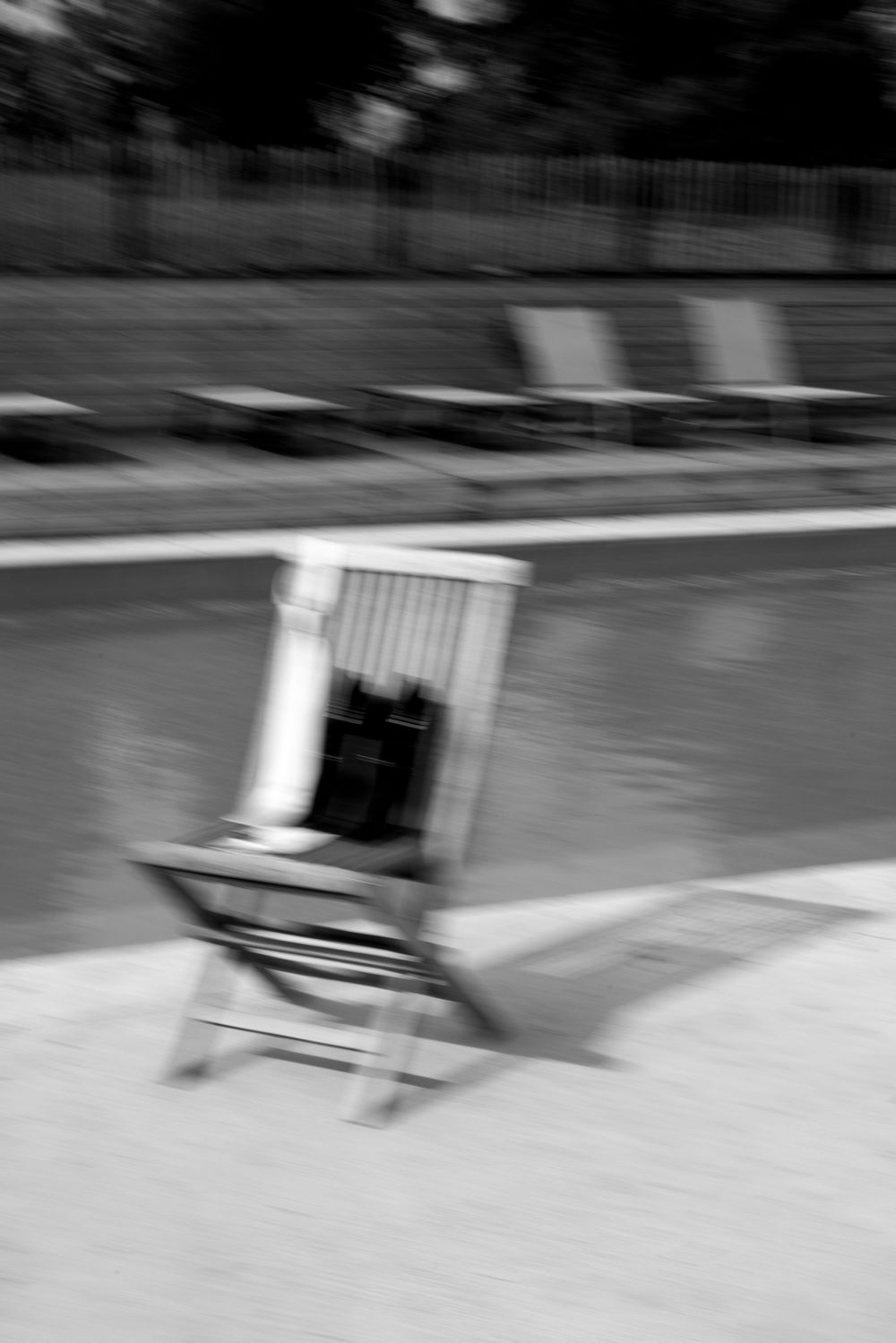 Motion blur of white chairs being moved across a paved surface.