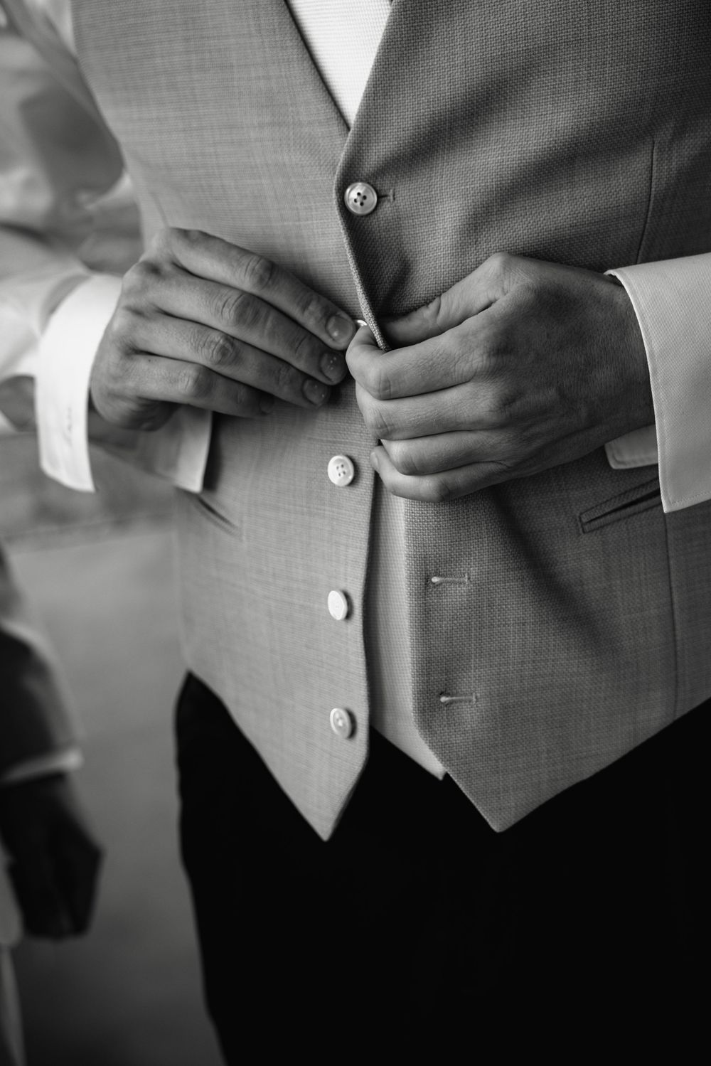 Close-up details of grey suit vest buttons and adjustments.
