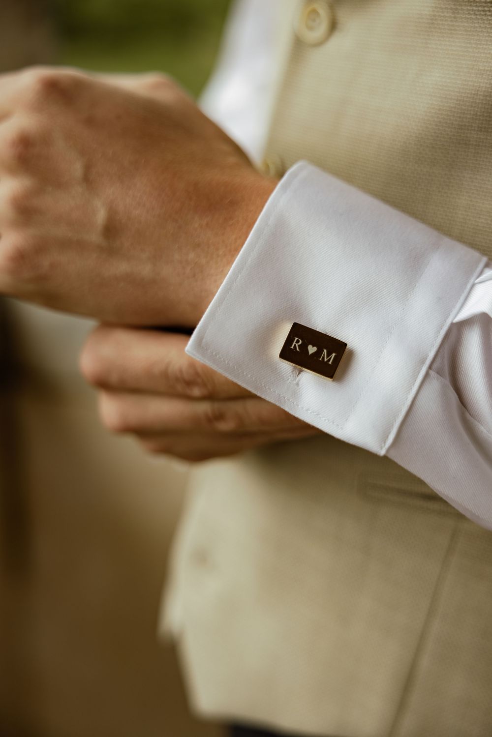 Close-up of white dress shirt cuff with monogrammed cufflink.