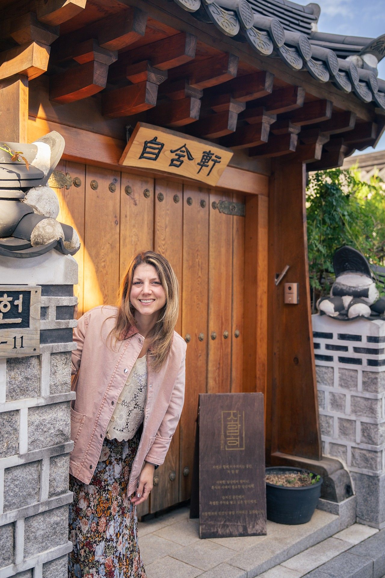 Couple sitting together on the wooden porch of a traditional Korean hanok house with tiled roof and decorative walls.