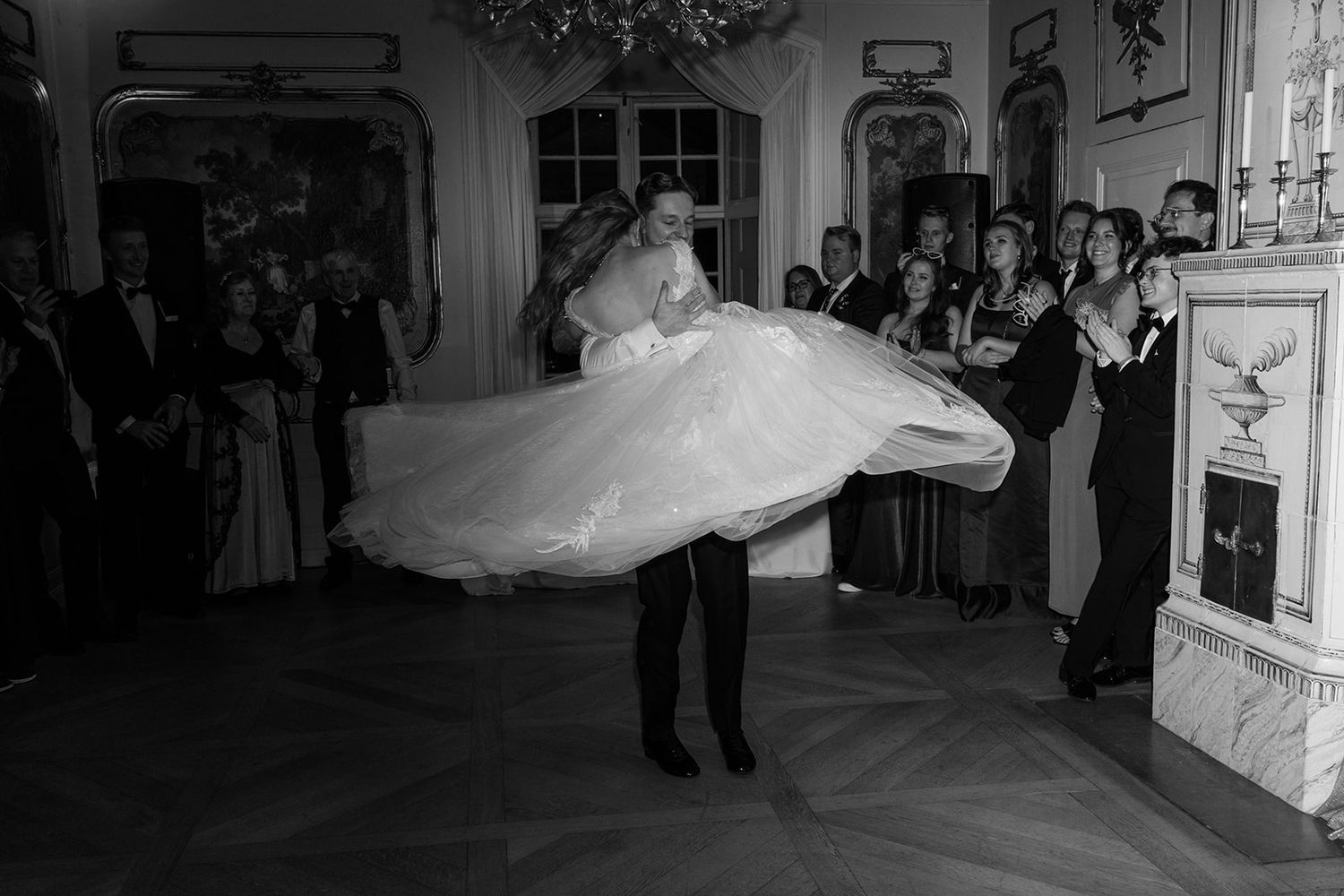 A wedding couple dances together at their reception while guests watch from the sidelines.