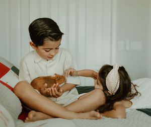 Children playing together on white bedding in natural light.