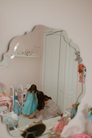 A pink bedroom with white furniture and mirrors reflecting decorative elements.