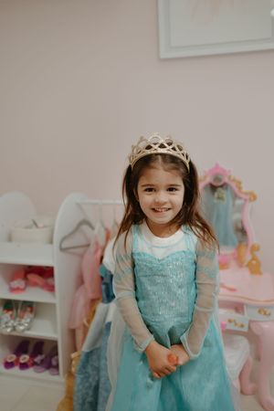 A child's bedroom decorated in pink and turquoise with dress-up clothes and accessories.