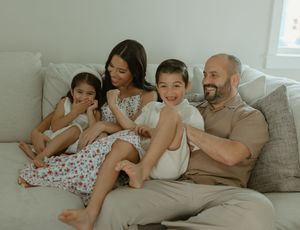A family lounging together on a comfortable gray sofa.