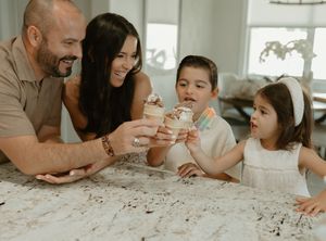 A family sharing snacks and conversation at a white kitchen counter.