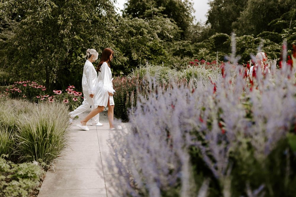 Couple walking along garden path with blooming lavender and ornamental grasses on a summer day.