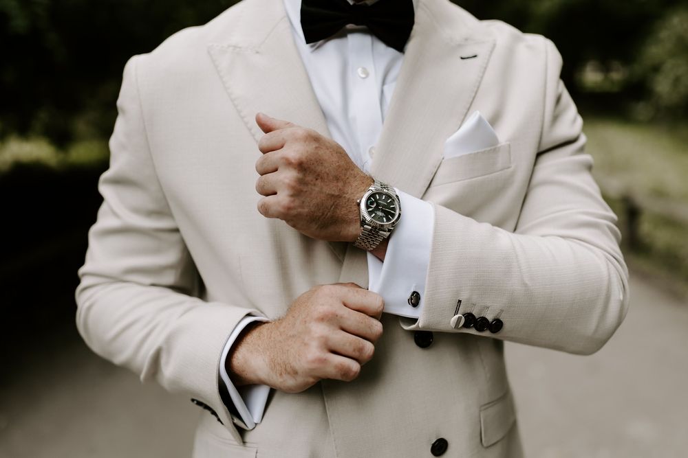 Close-up details of a light beige suit jacket and cufflinks at an outdoor event.
