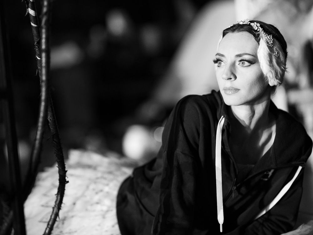 Black and white portrait of a young woman wearing a headband, gazing upward in a contemplative pose.