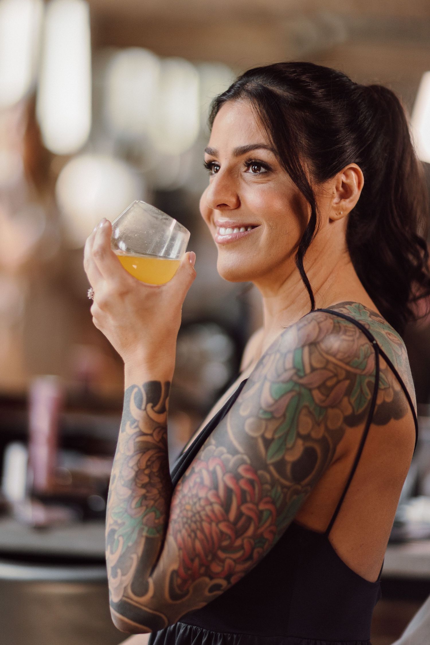 Person with colorful sleeve tattoos enjoying a drink at an event.
