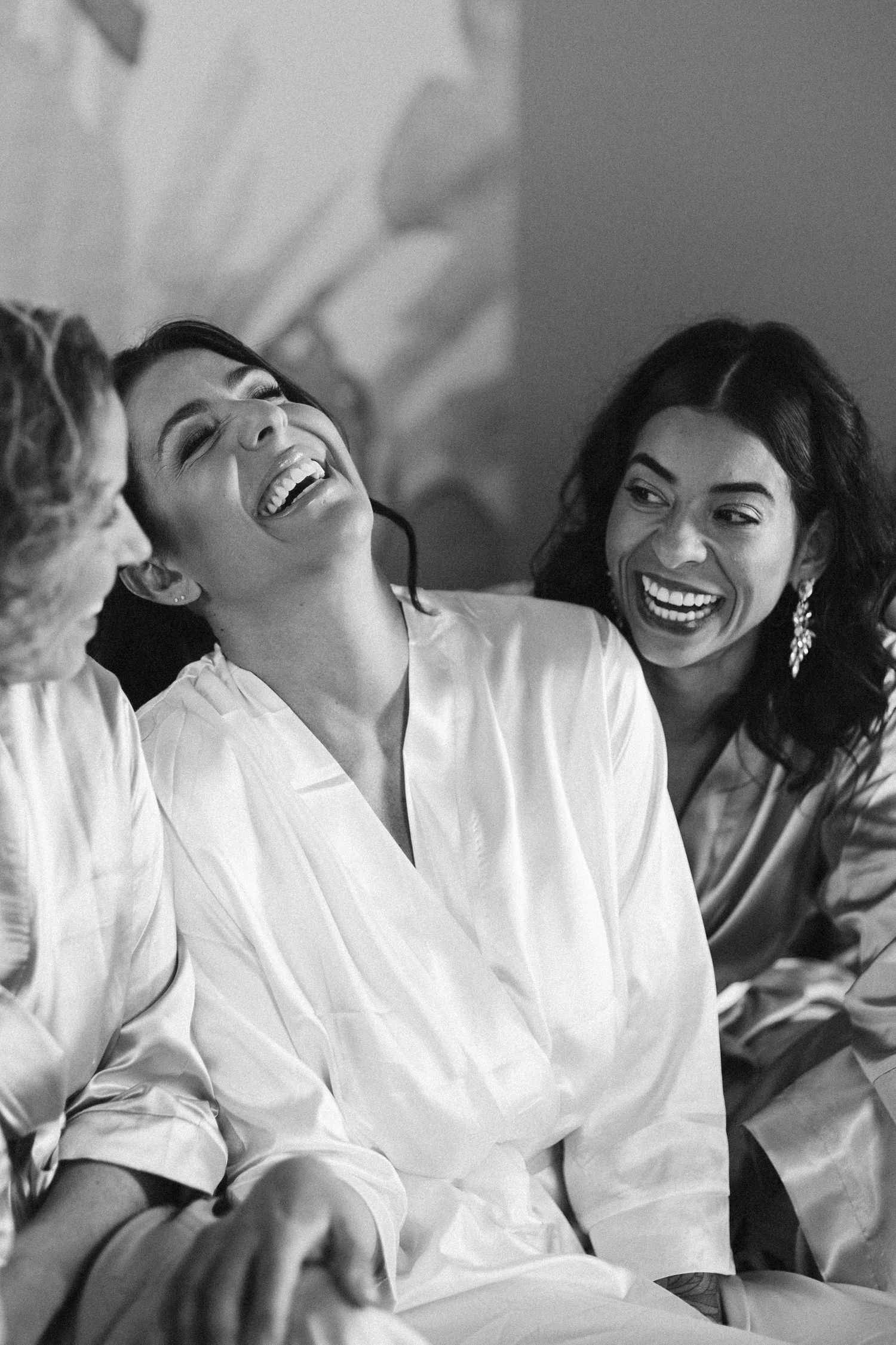 Candid black and white photo of people laughing while wearing white robes.