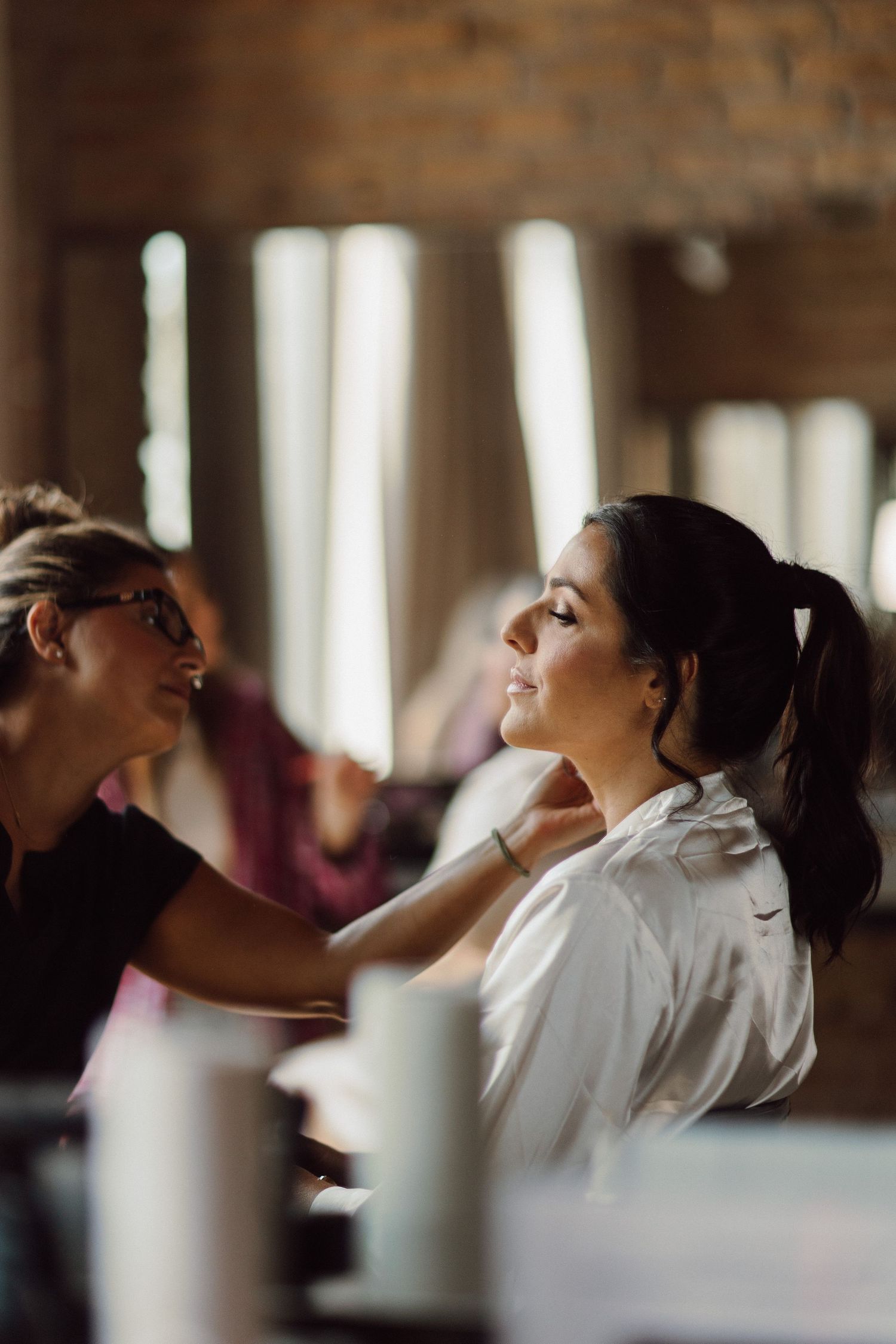 Wedding preparation scene in a rustic venue with exposed brick and natural lighting.