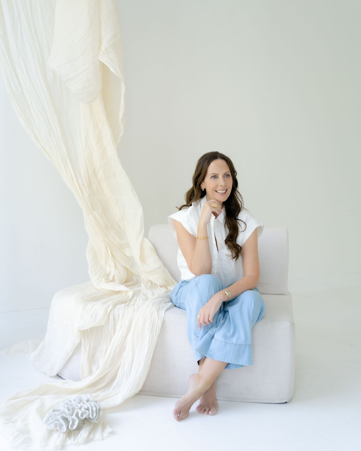 Person sitting on white couch in minimalist white room setting.