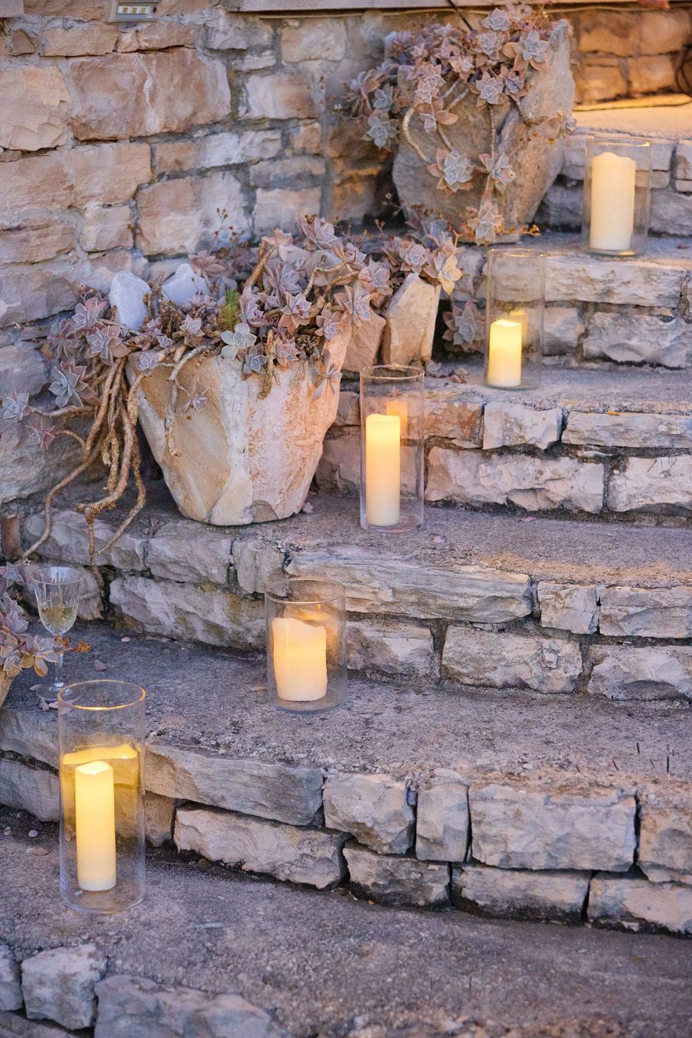 Glowing candles arranged on rustic stone steps create a romantic ambiance at dusk.