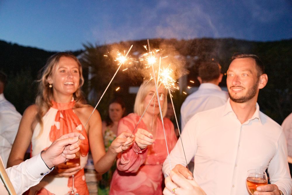 Wedding guests holding sparklers during an evening celebration creating a festive atmosphere.