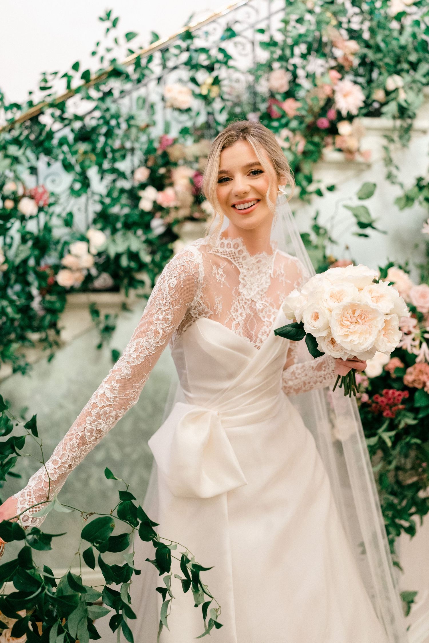 Ethereal bridal portraits with lace sleeves amid pink garden roses.
