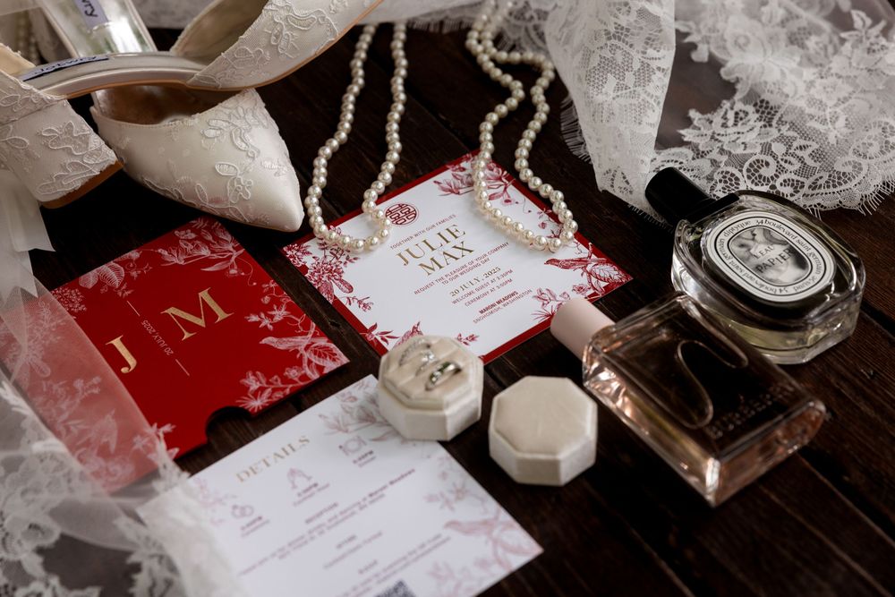 Wedding details including lace veil, invitation cards and decorative items arranged on dark wooden surface.