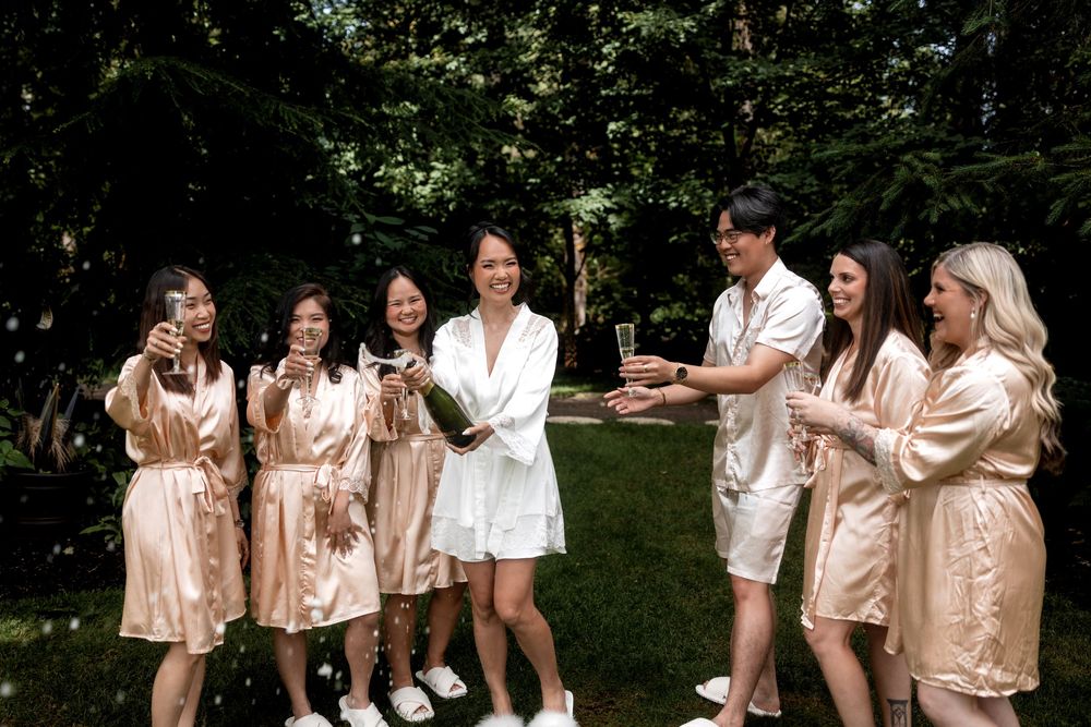Wedding party members wearing matching champagne-colored satin robes posing together outdoors.