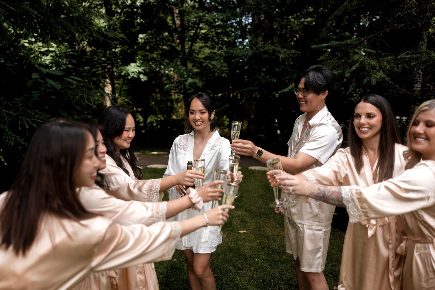 A group wearing matching light pink outfits celebrates in a sunny outdoor garden setting.