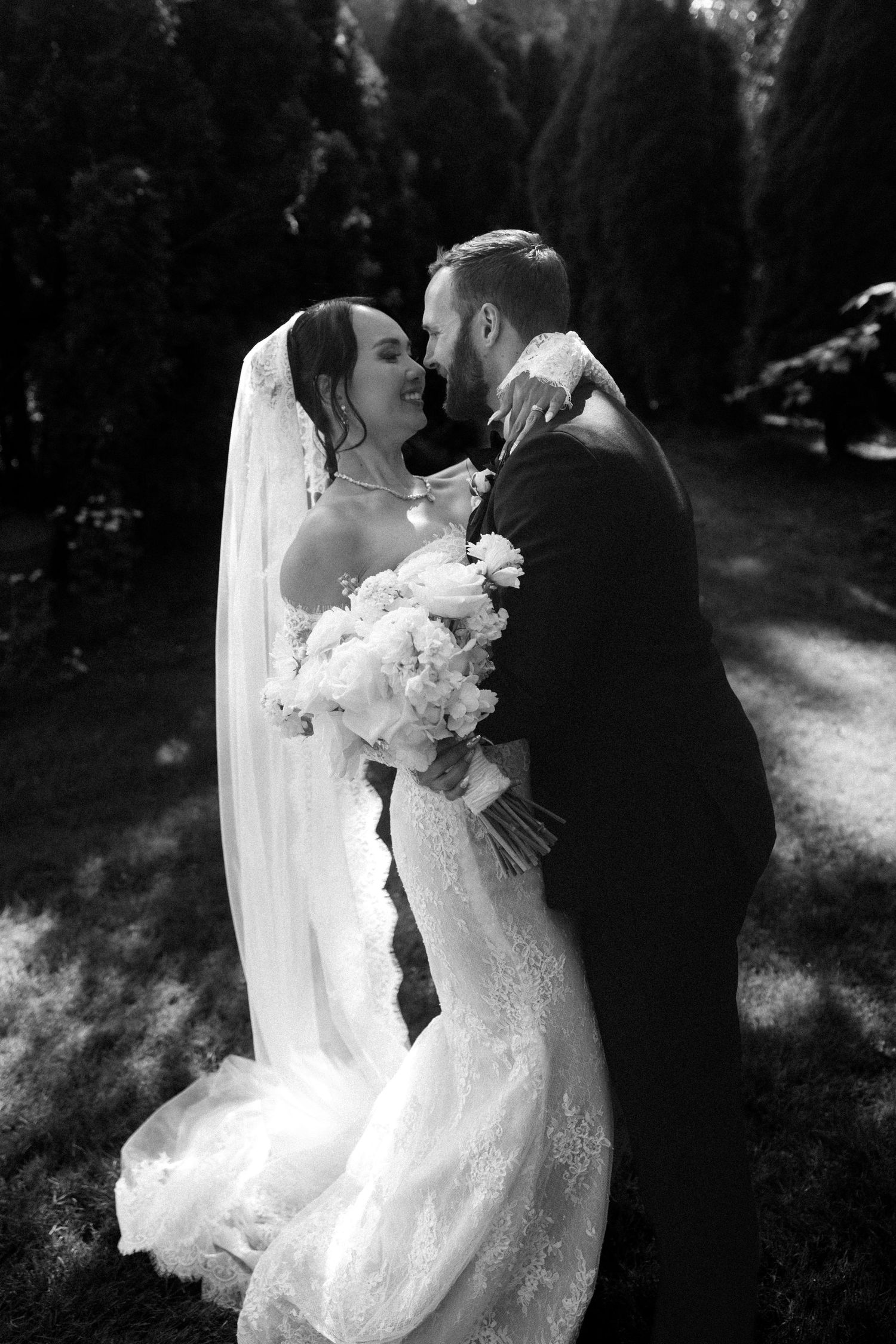 Elegant black and white wedding portraits showing intimate moments between newlyweds in outdoor setting.