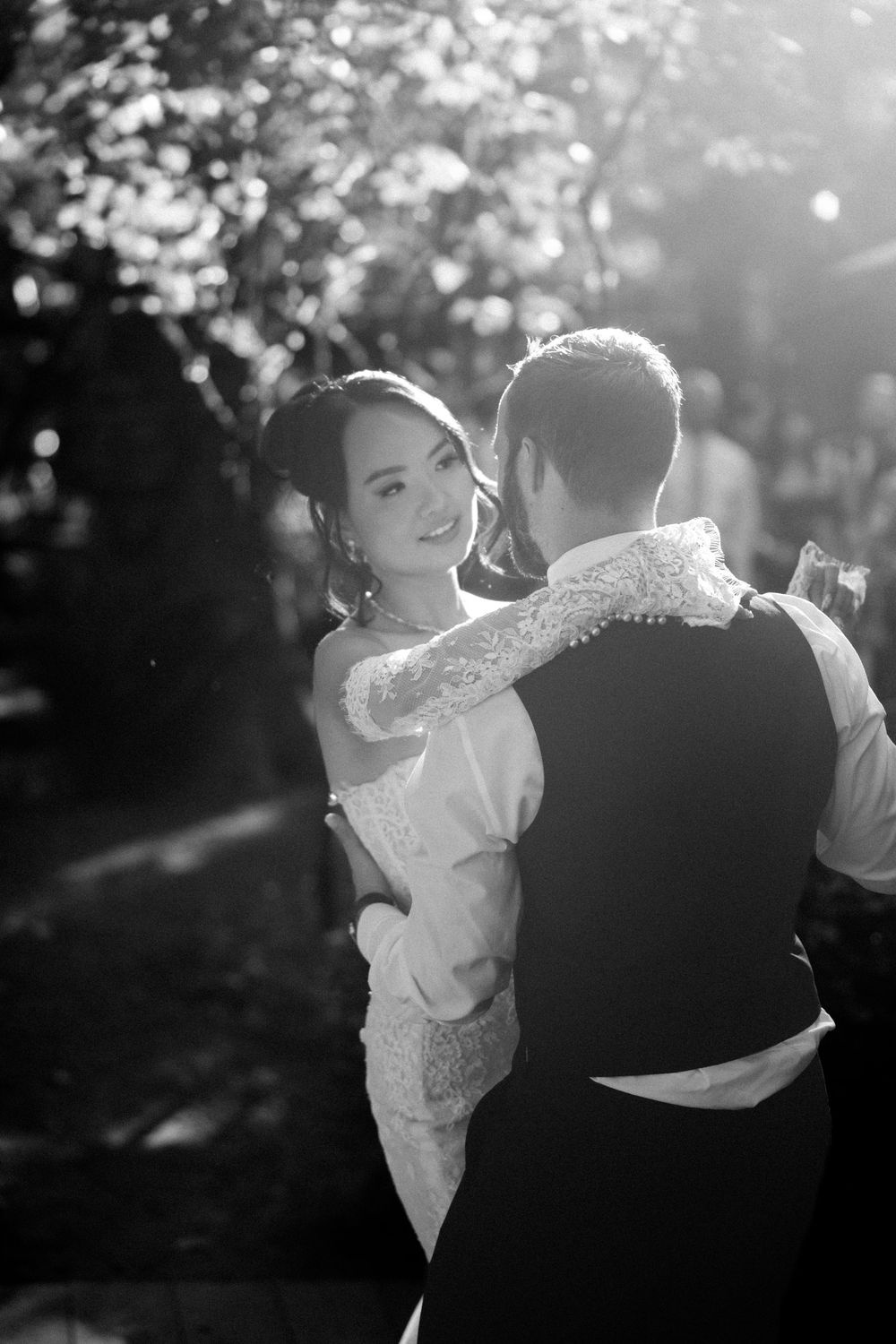 A couple shares a romantic dance together during sunset at their outdoor wedding celebration.