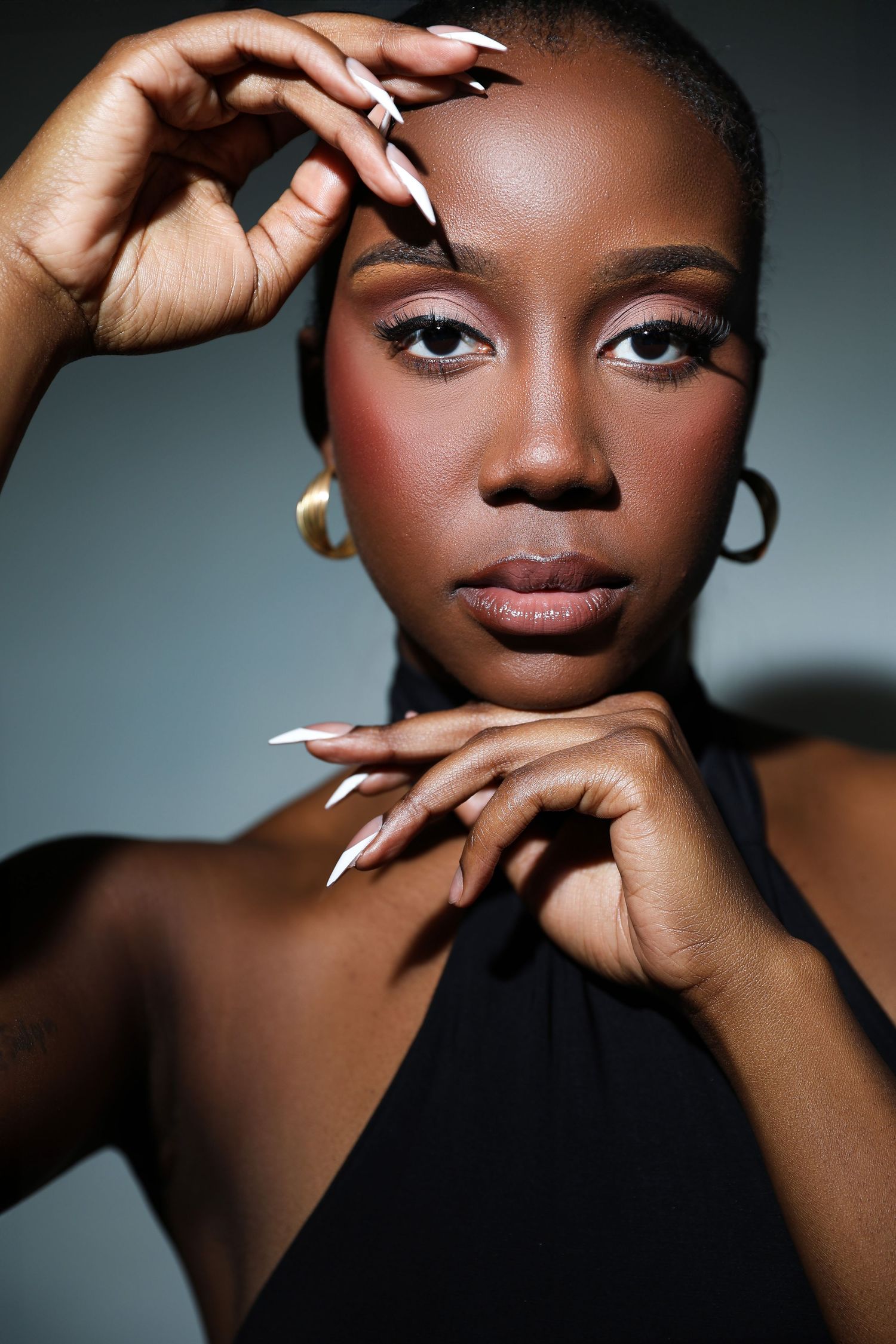 A series of artistic beauty portraits showing elegant poses with long white manicured nails against a dark background.