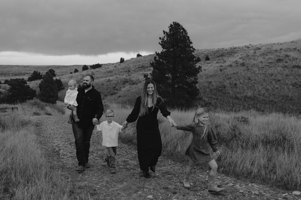 A group of people walking together through rolling hills and grasslands on a cloudy day.