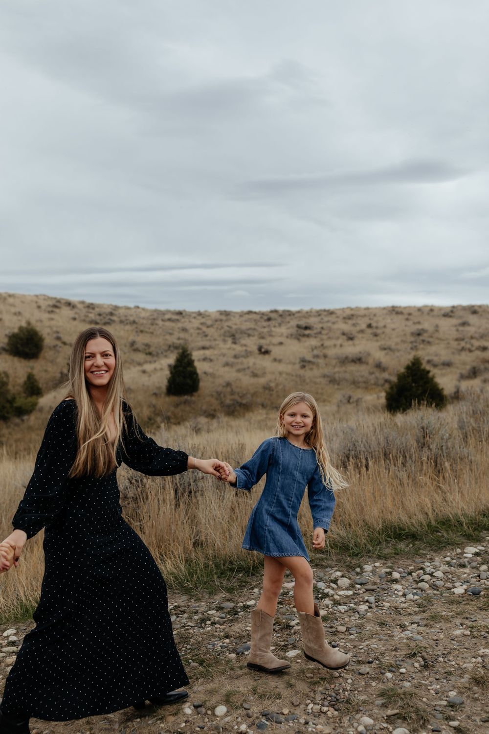 A family enjoys a playful moment together while exploring a rugged desert landscape on an overcast day.