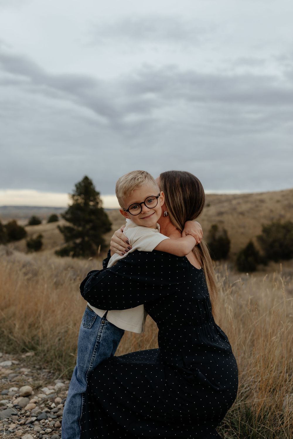 Emotional family portraits captured against a cloudy mountain backdrop during an outdoor photography session.