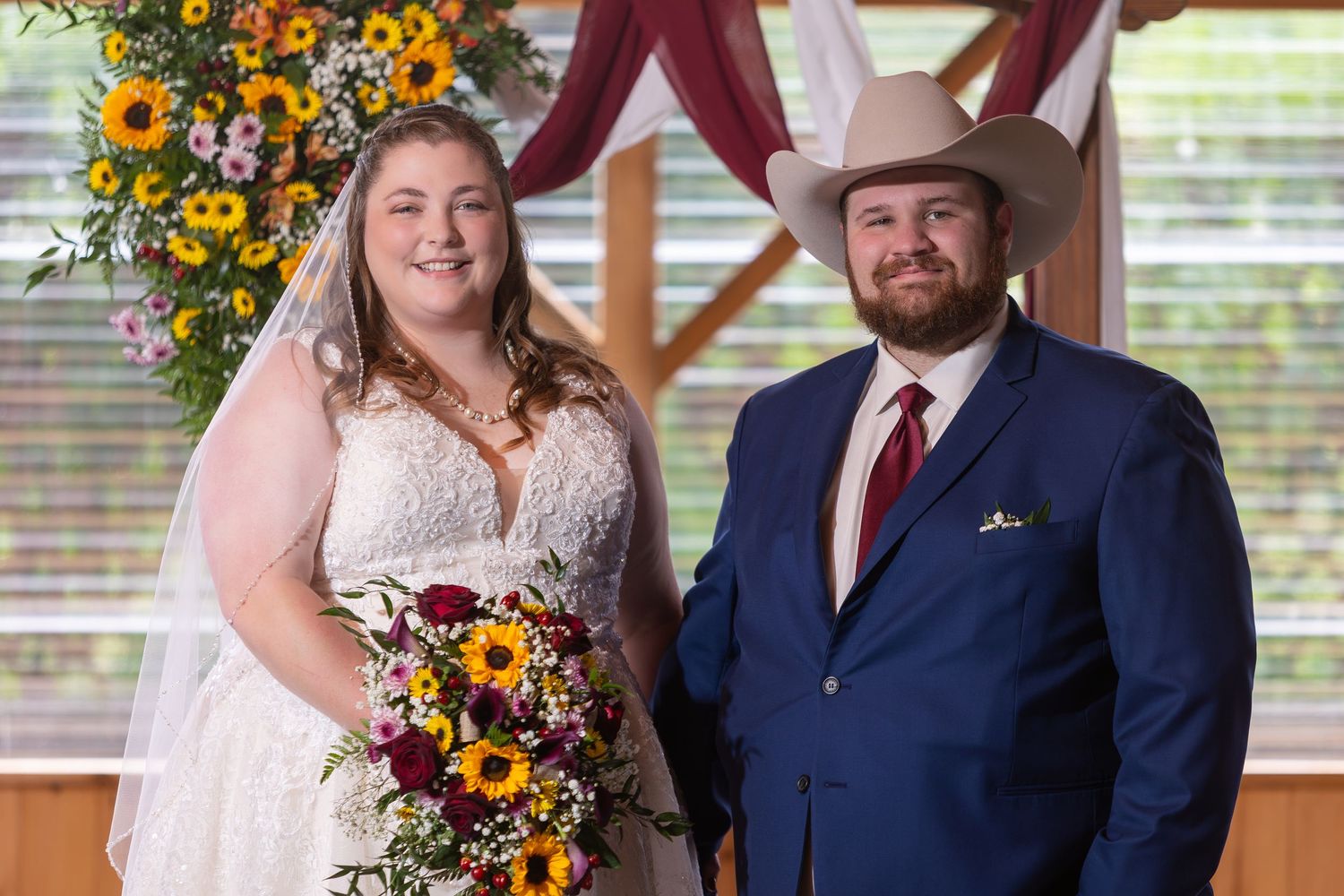 Wedding party poses in rustic venue with autumn sunflowers and fall decor.