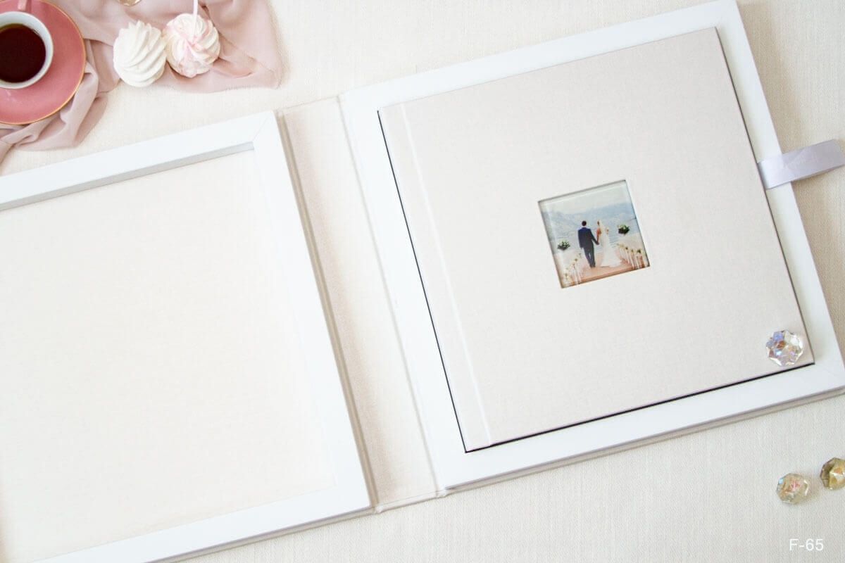 White photo album open to display a small mounted photograph with decorative binding.
