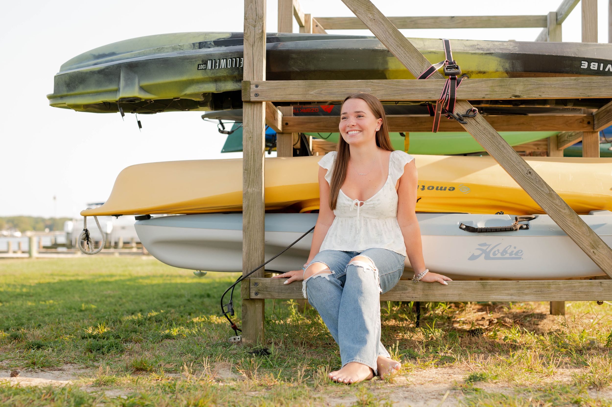 Sitting beneath stacked kayaks and canoes on outdoor storage rack.