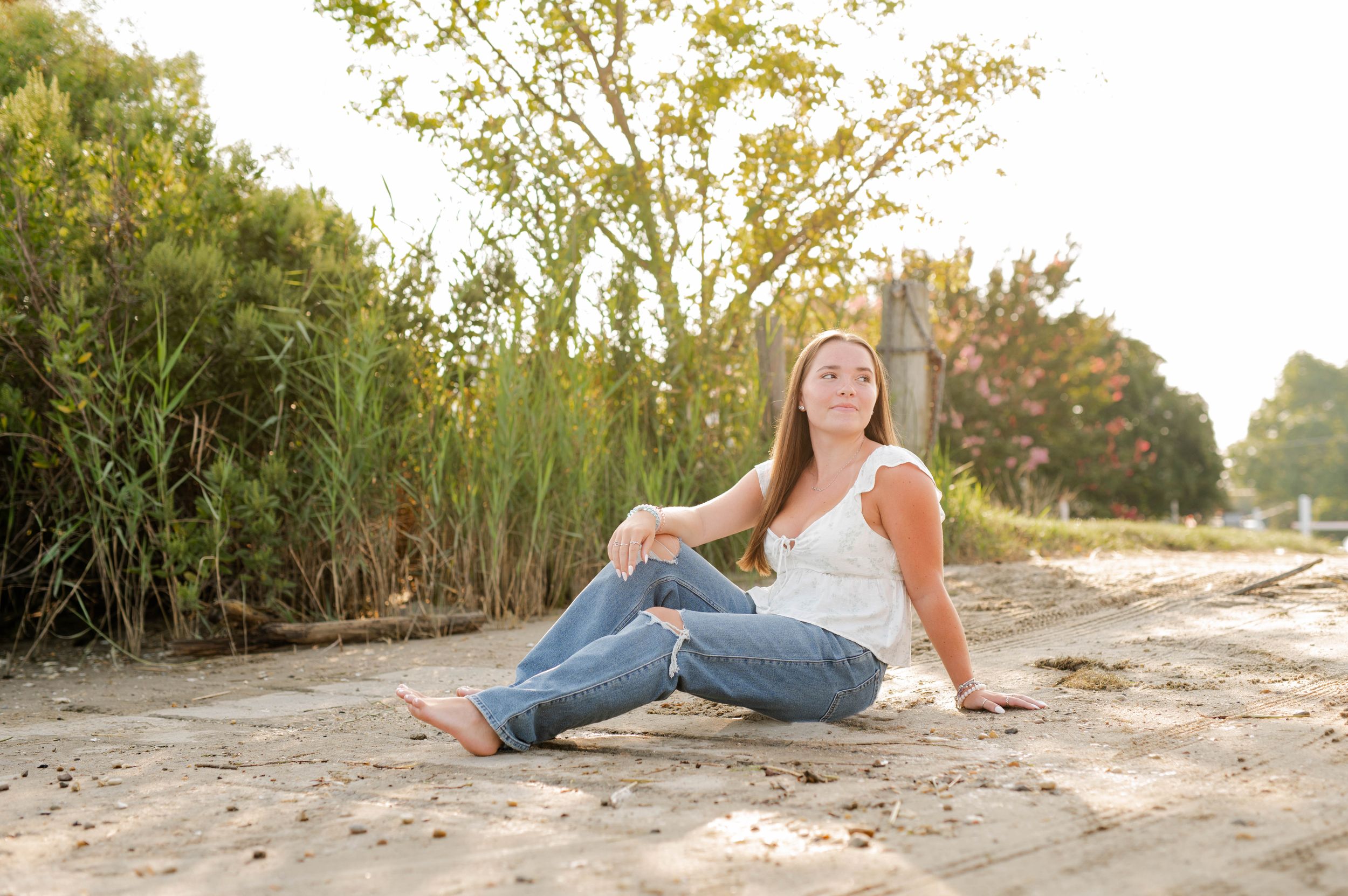Casual portrait session on sandy beach with tall grass and trees in background.