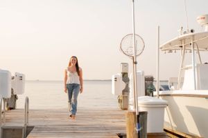 Walking along wooden marina dock with boats and water in background.