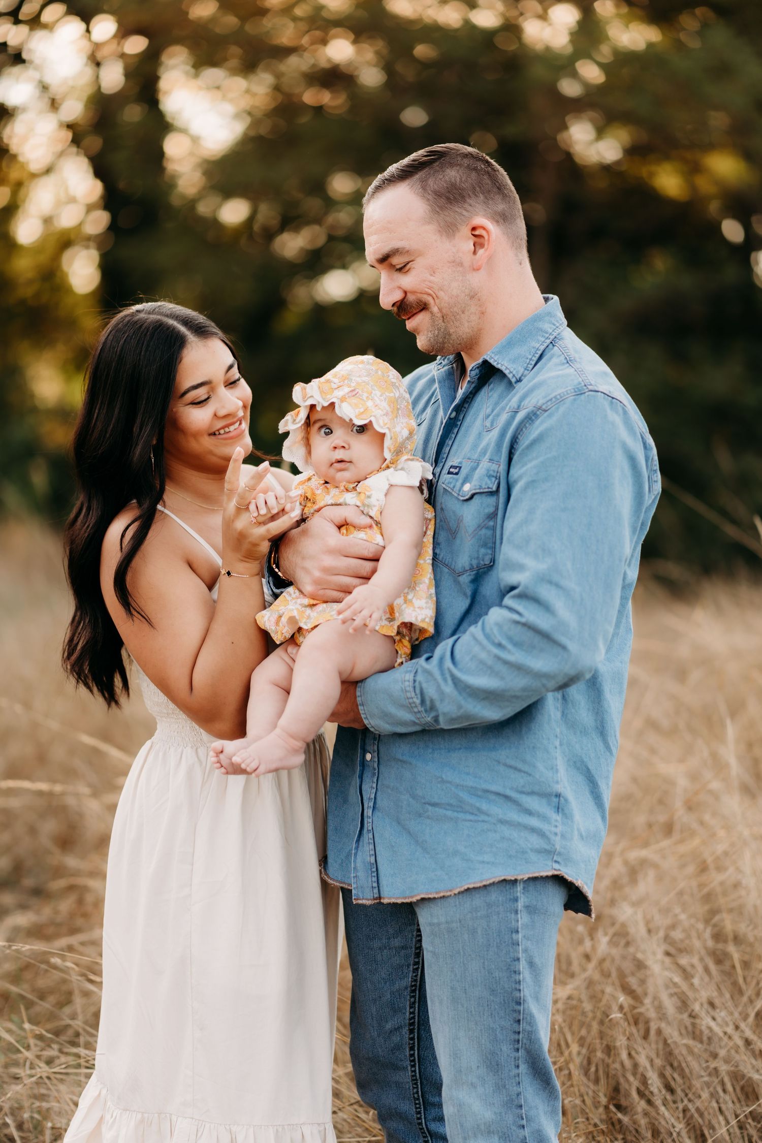 Family shares joyful moments together in a golden field during sunset, wearing casual blue and white outfits during family photos in Tacoma.