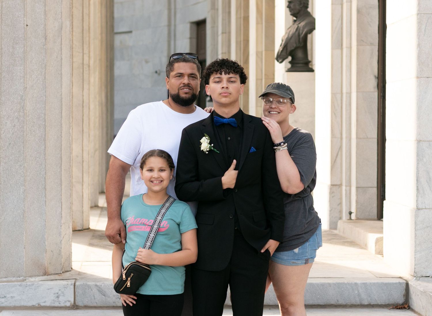 Group of people posing together in front of white columns at a tourist destination.