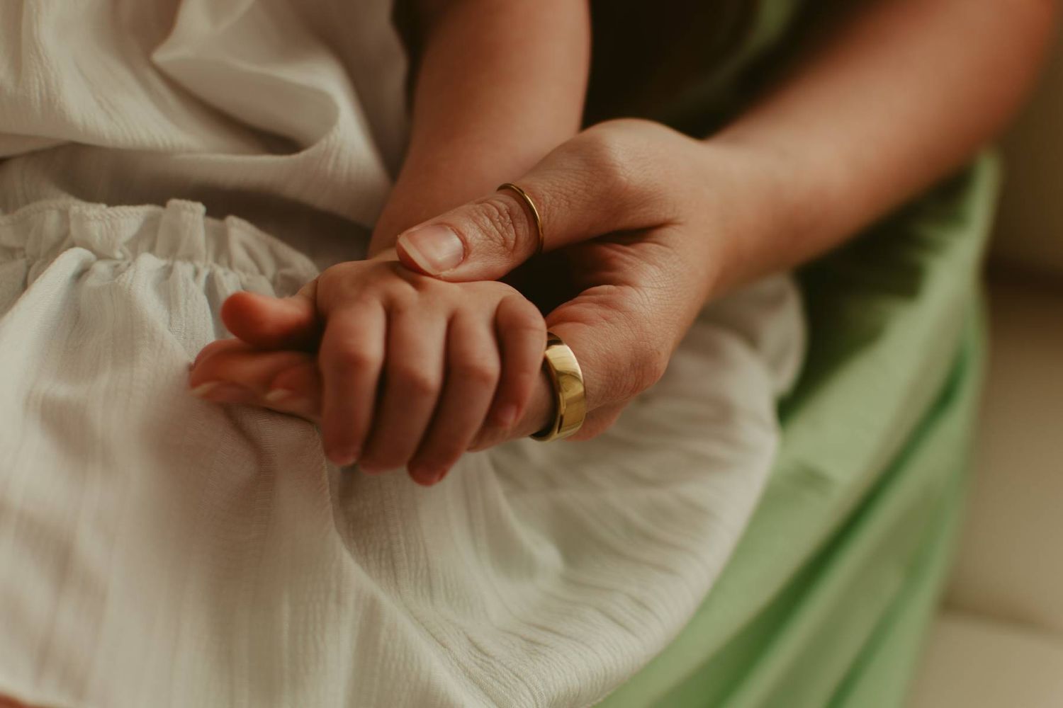 Close-up of hands touching gently against white fabric.